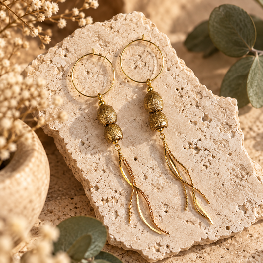 a pair of gold real gumnut earrings displayed on a stone slab